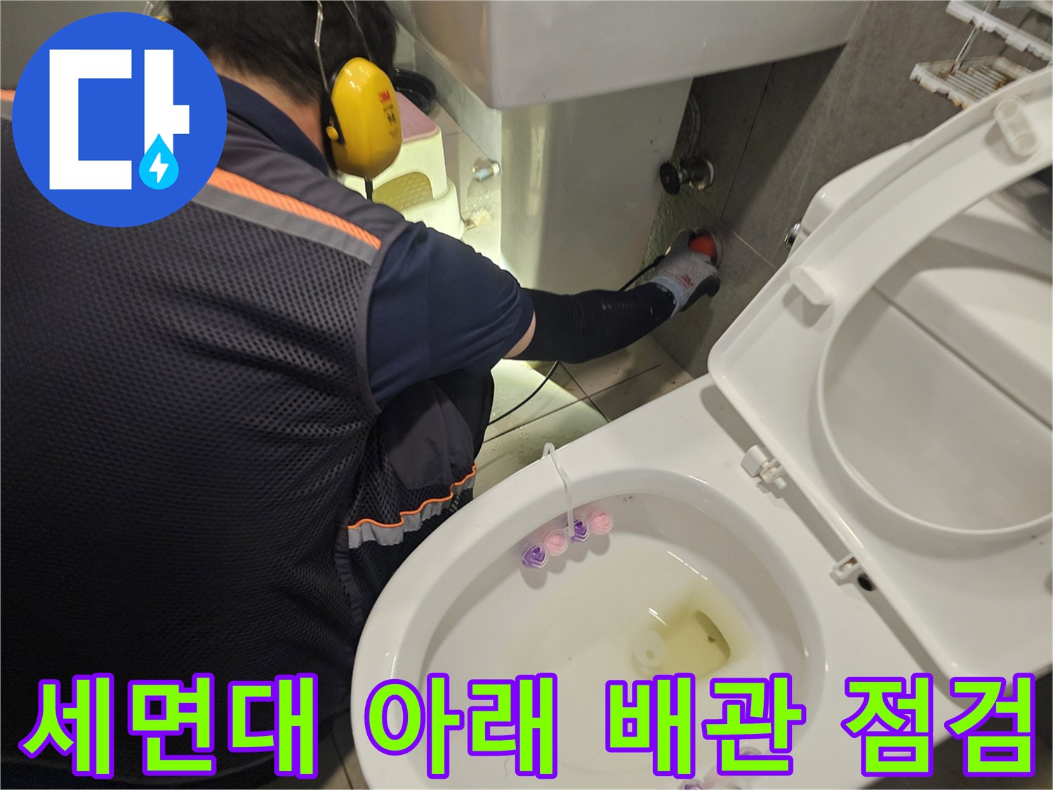변기와 세면대 사이의 배관 연결 상태를 확인하는 작업자