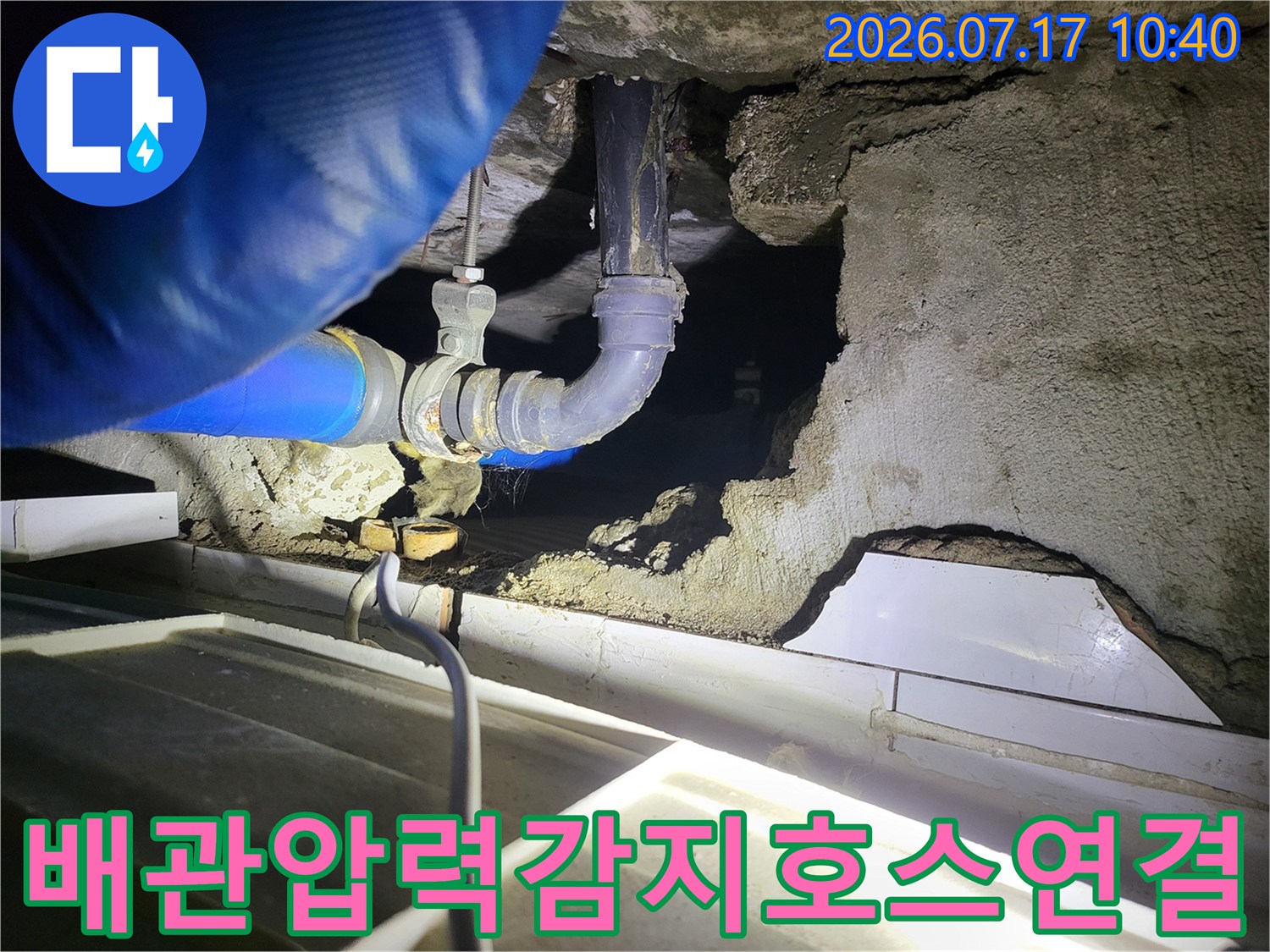 누수 지점 파악을 위해 천장 내 배관에 압력 감지용 호스를 연결하여 정밀 테스트를 수행하는 모습
