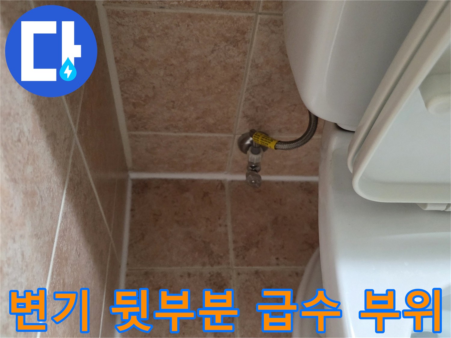 베이지색 타일 벽면에 고정된 황동색 밸브와 호스 연결 모습