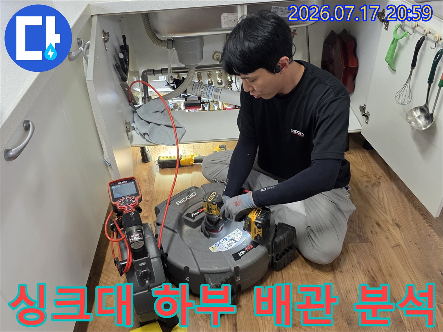 전문가가 싱크대 아래에서 탐지 장비로 배수 시스템을 정밀하게 점검하는 장면