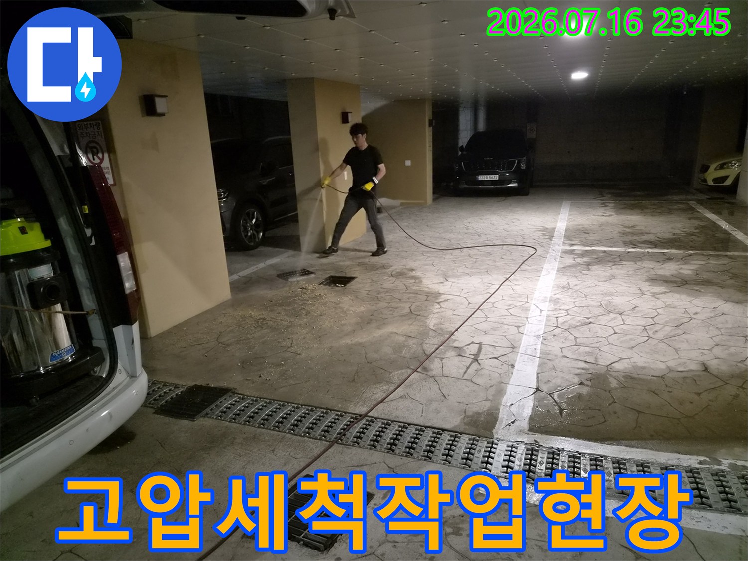 전문가가 배관 세척 장비를 사용하여 지하 주차장의 막힌 하수관을 뚫는 모습
