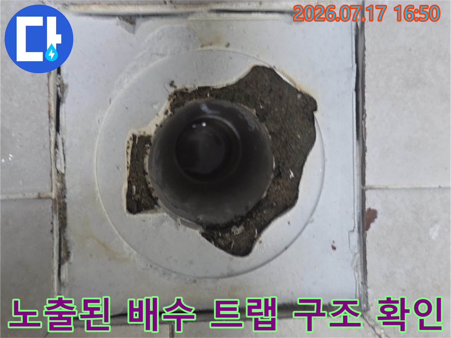 배수구 주변의 파손된 타일과 노출된 배관 연결부