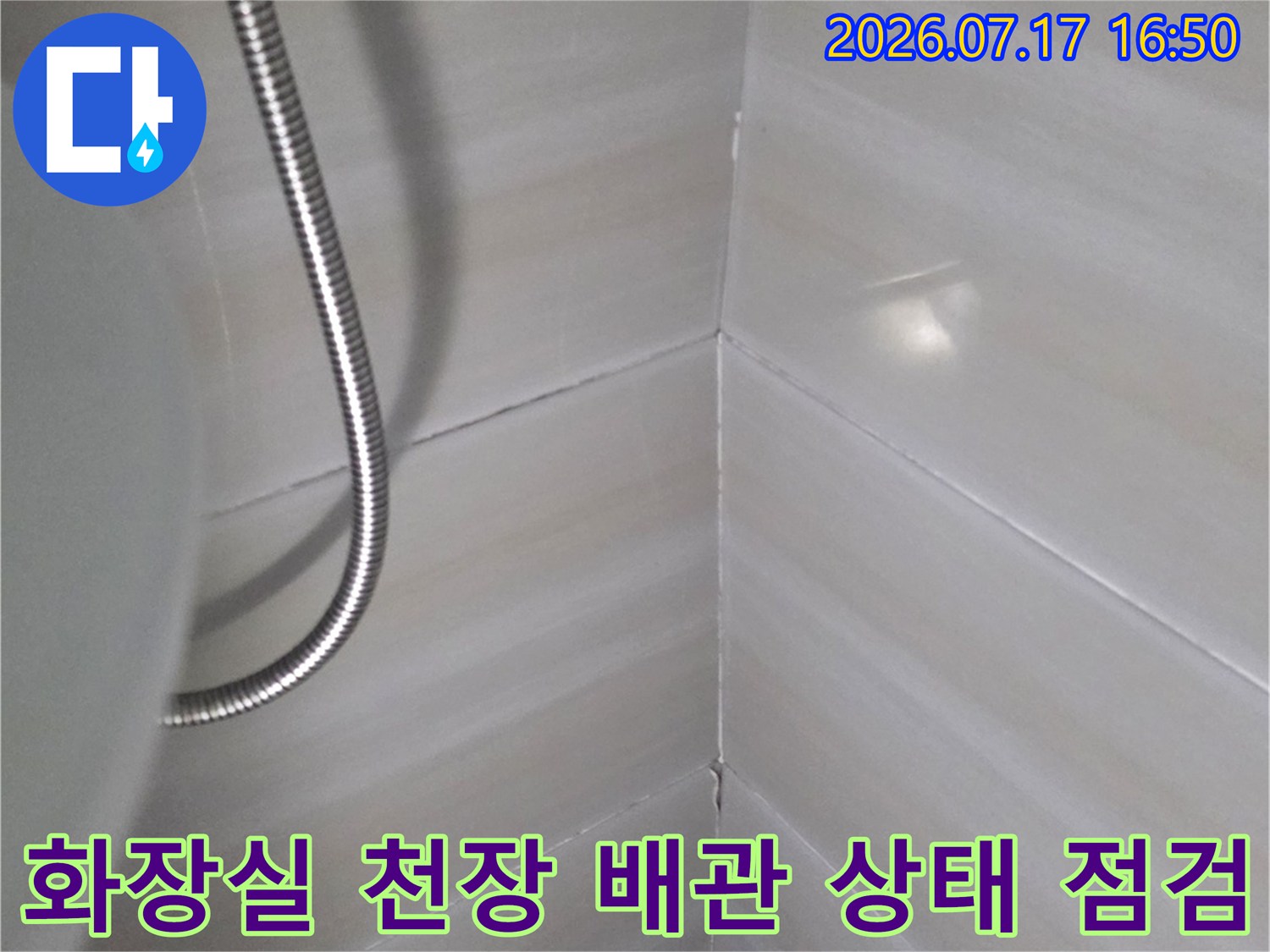 흰색 타일로 마감된 화장실 천장과 금속제 유연한 배관-샤워 호스-모습