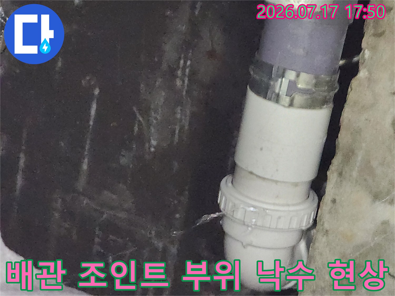 흰색 배수관 굴곡진 연결부에서 아래로 물이 흐르고 있는 누수 지점 사진