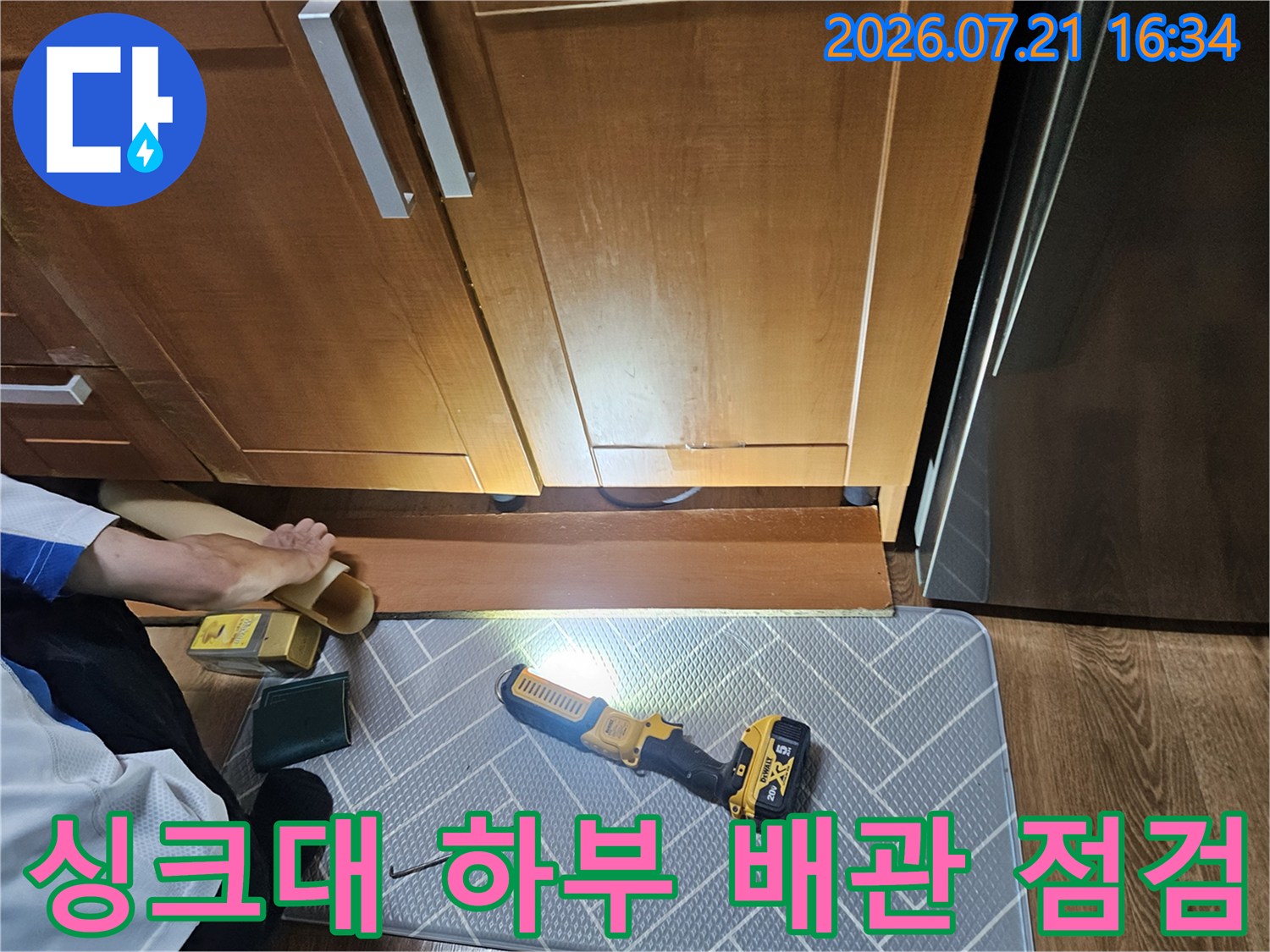 싱크대 밑 공간에서 작업자가 전문 장비로 배관 상태를 확인하는 모습