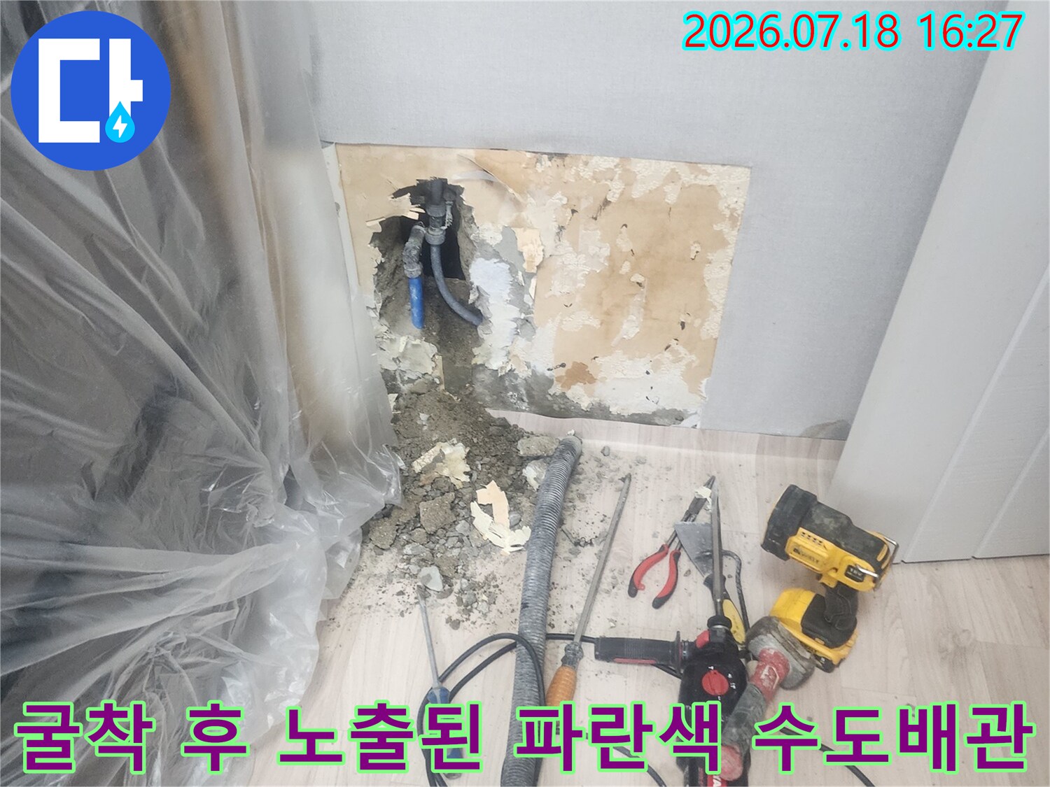 바닥을 파내어 드러난 파란색 배관-주변에 전동공구와 청소 호스가 연결되어 있음