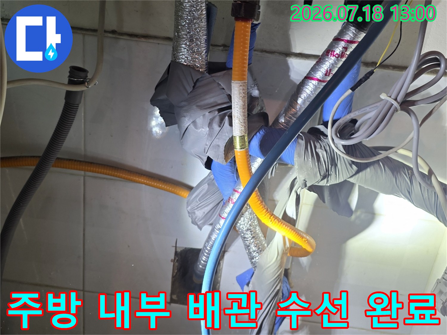 보온재로 덮인 은색 관과 노란색 주름관-파란색 호스가 연결된 복잡한 배관망