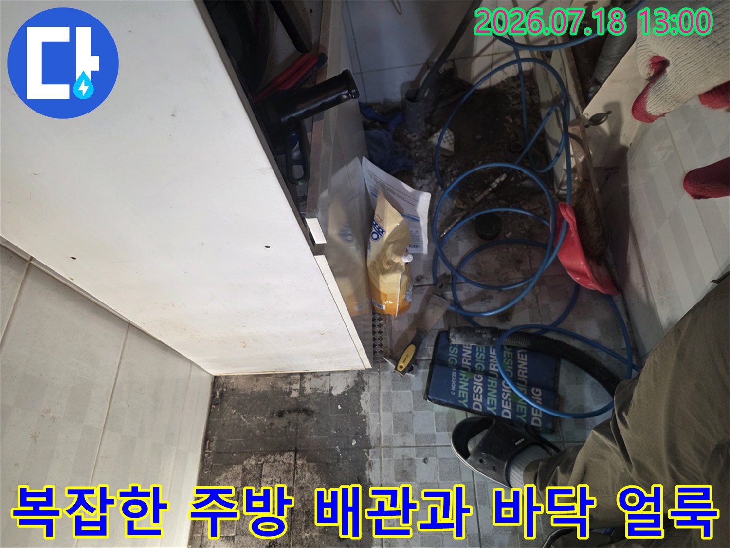 싱크대 아래 푸른색 배관들과 물기에 젖은 타일-누수 지점 탐색 중
