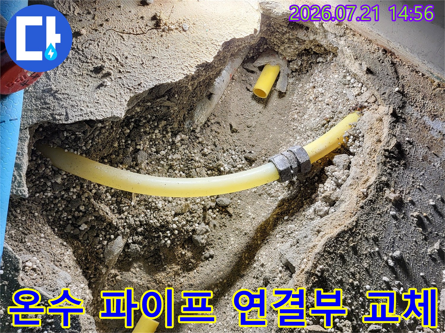 파손된 노란색 온수 배관을 새 부속으로 대체하는 시공 현장 사진