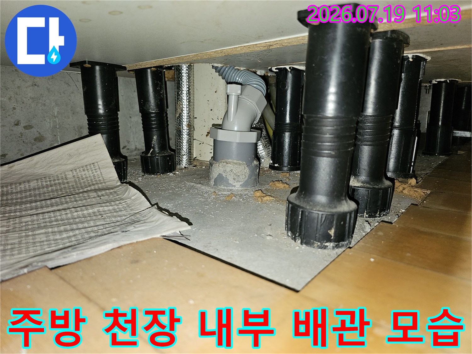 아파트 주방 천장 내부의 검은색 배관 지지대와 드레인 배관-연결 부위 모습