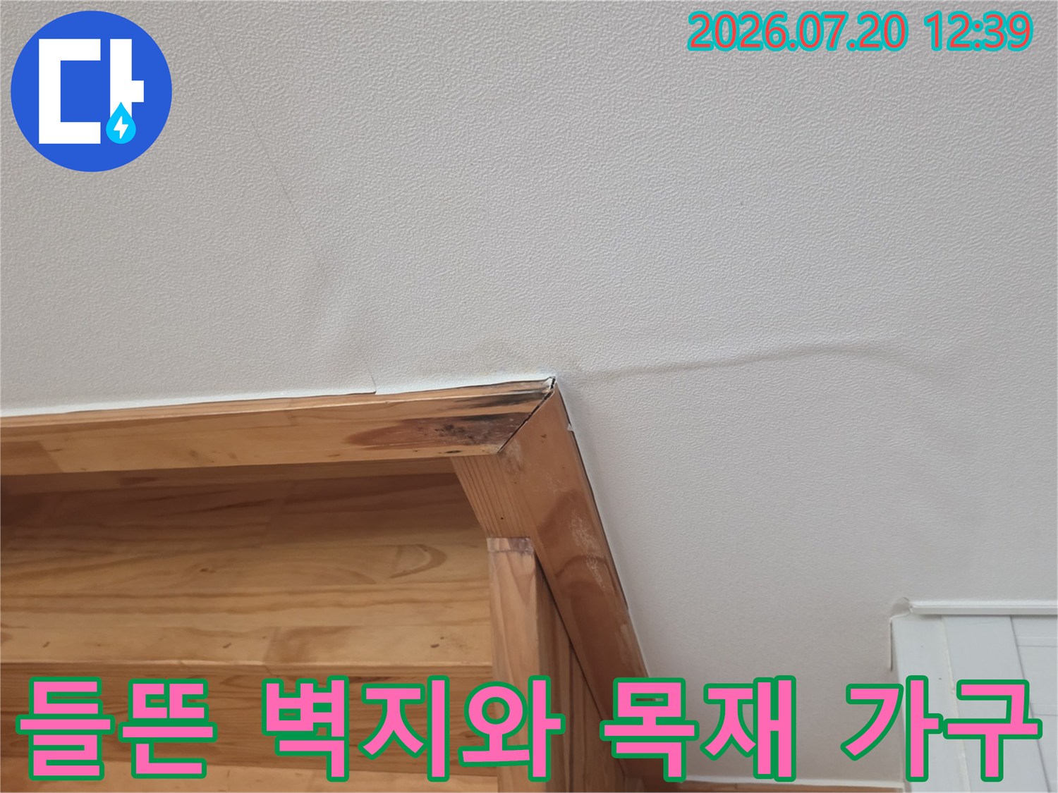 나무 선반과 맞닿은 벽지가 습기에 의해 울퉁불퉁해진 모습