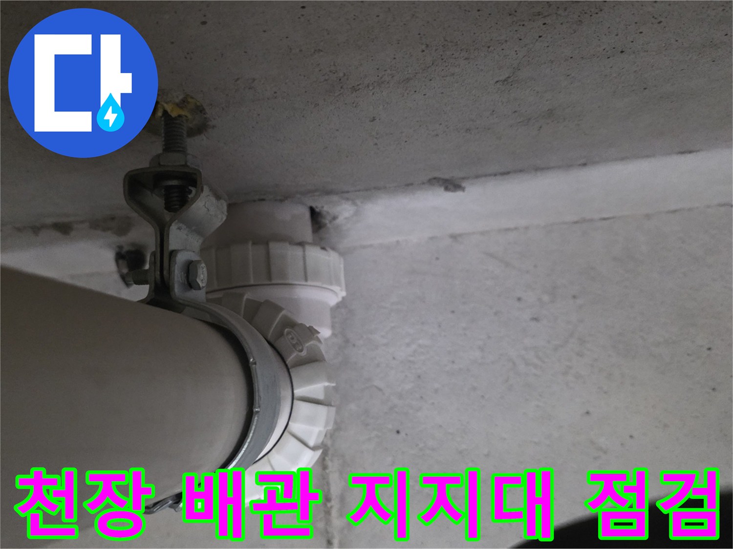 천장 구조물에 고정된 굵은 배관과 금속 고정 장치