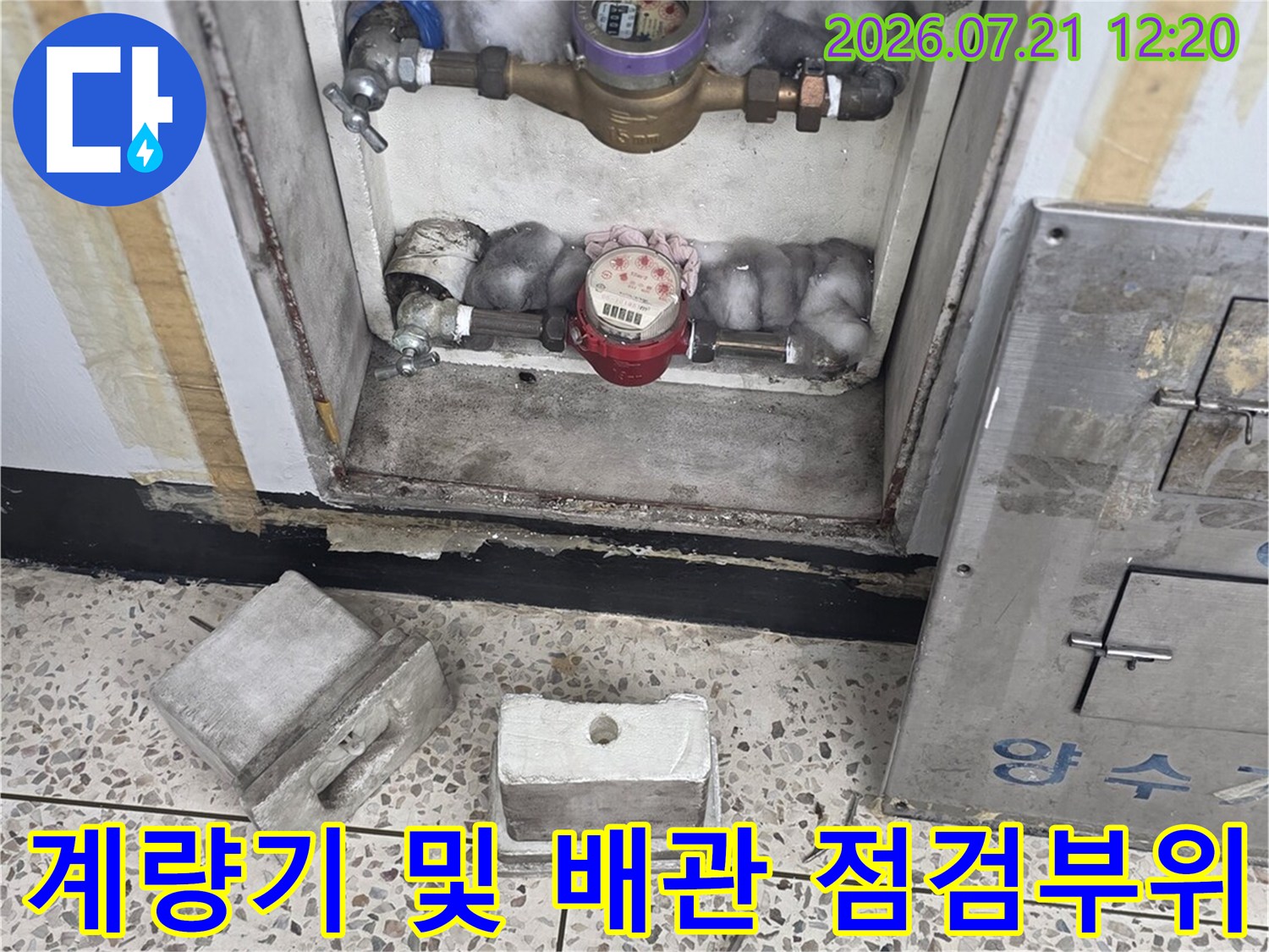 베란다 계량기와 수도배관 연결부를 세밀하게 관찰하는 장면
