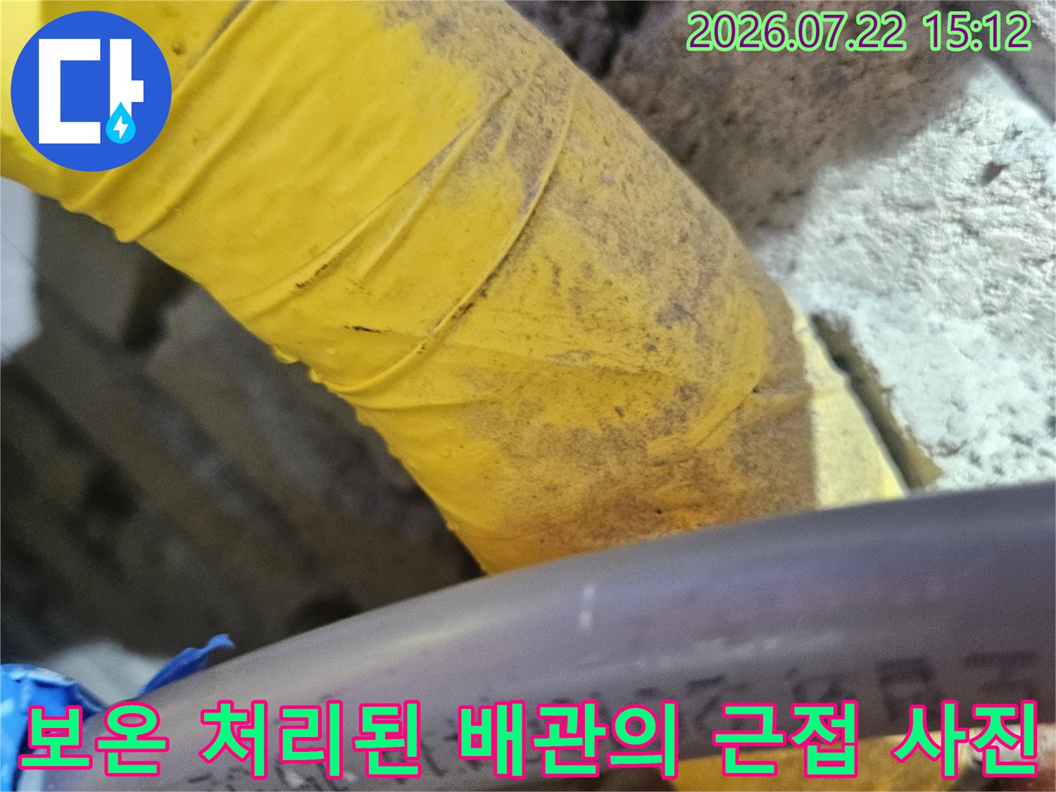 노란색 보온재로 덮인 배관과 그 옆으로 배치된 회색 플라스틱 배관-누수 점검 모습