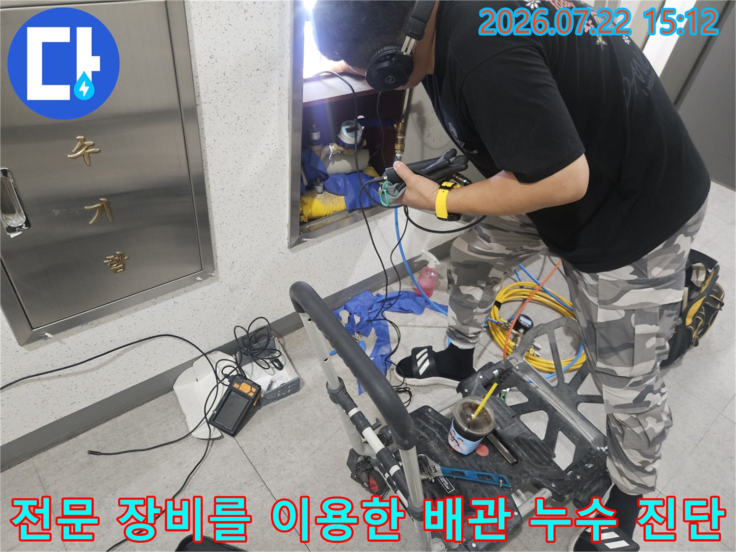 엔지니어가 청음 탐지기와 헤드셋을 사용하여 벽 내부의 누수 지점을 세밀하게 추적하는 사진