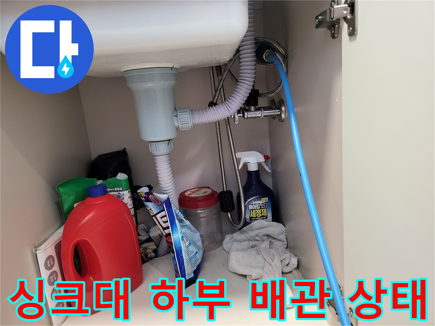 주방 싱크대 하부의 배수 호스와 급수 밸브 연결 부위 모습