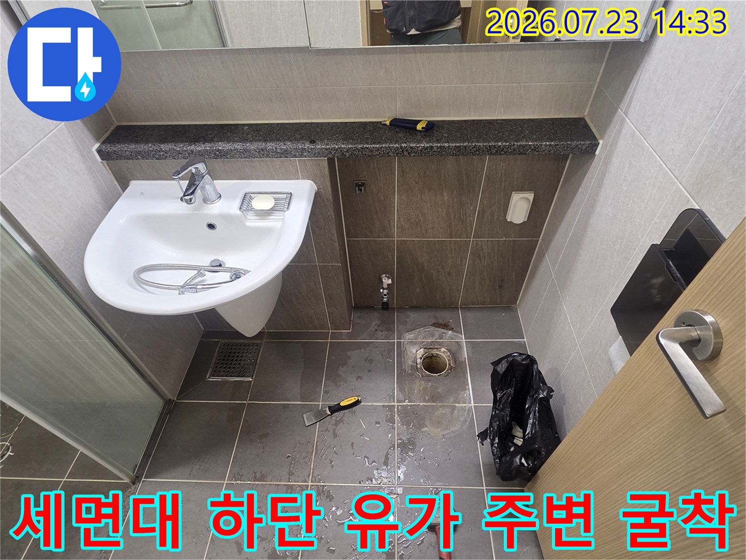 화장실의 세면대 아래쪽 타일을 제거하고 배수관 입구가 드러난 누수 진단 현장