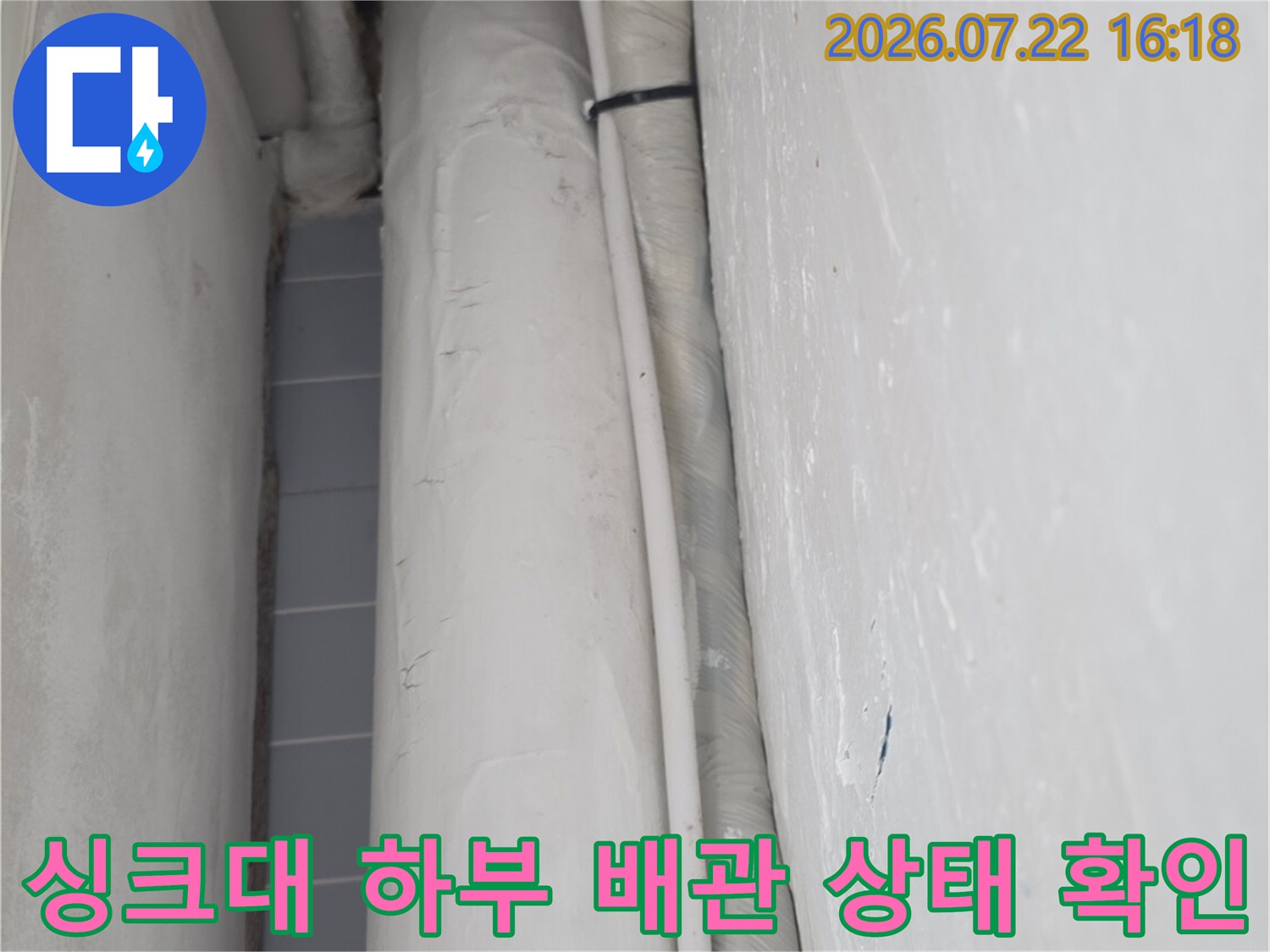 주방 싱크대 아래쪽의 흰색 보온재로 감싸진 배관과 천장 마감재 모습
