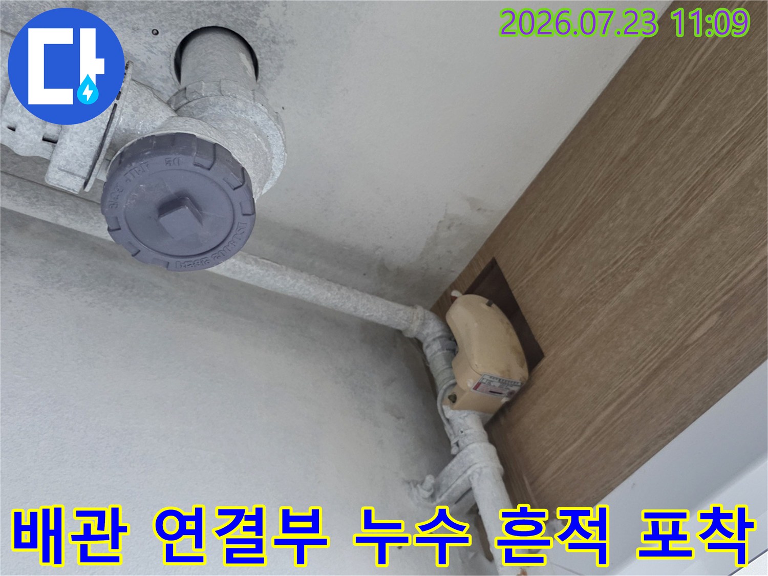천장에 설치된 배관과 갈색 마감판 사이의 습기 및 오염 상태-사진