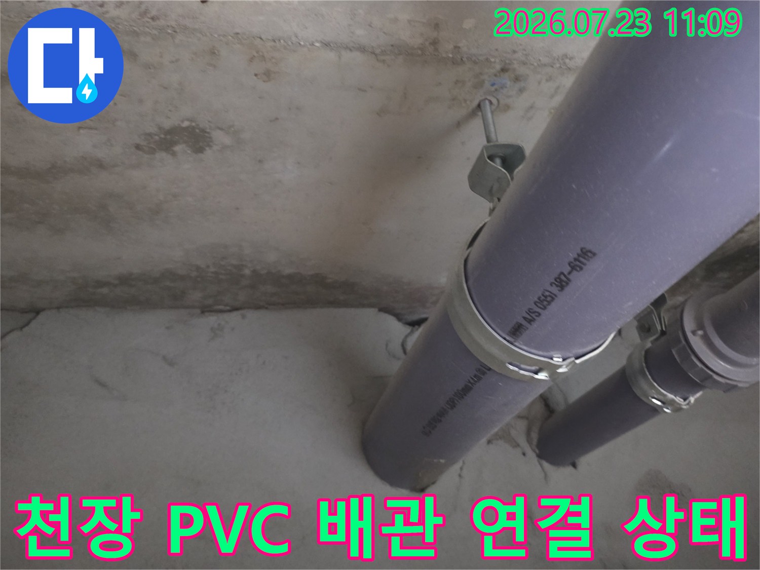 콘크리트 천장에 고정된 회색 PVC 배관과 금속제 고정 밴드-연결 부위 확인 모습