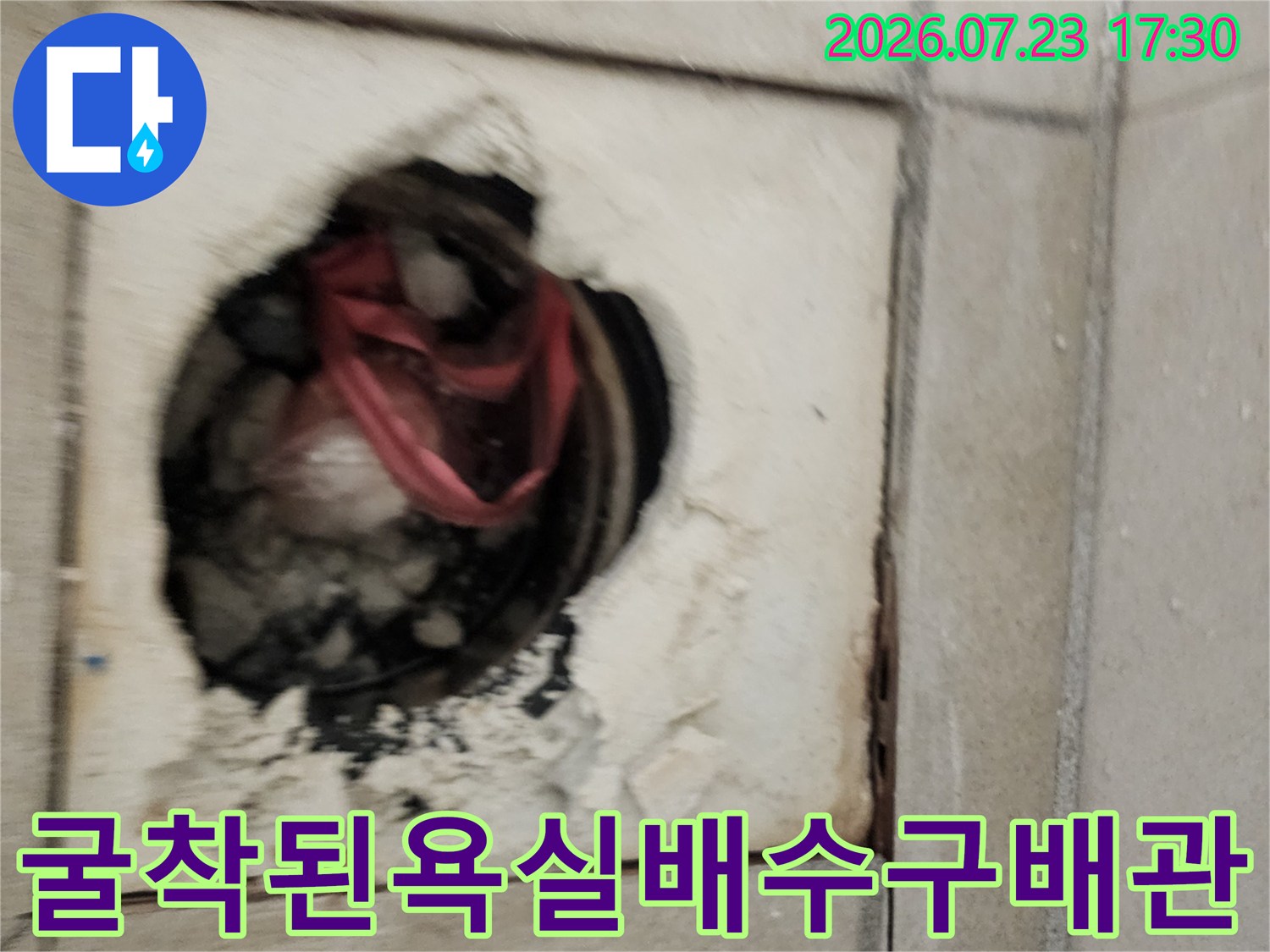 타일을 제거한 후 드러난 붉은색 하수 배관과 주변의 부서진 콘크리트 파편들