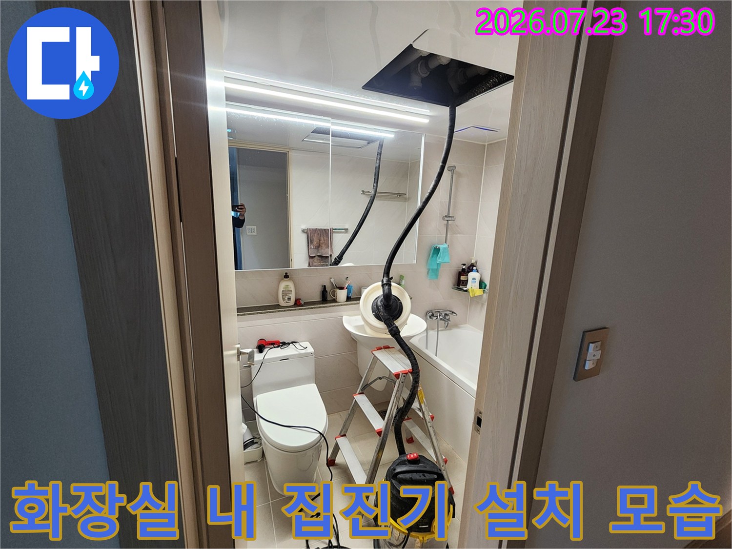 화장실 내부-변기와 세면대 옆에 배치된 산업용 집진기와 사다리