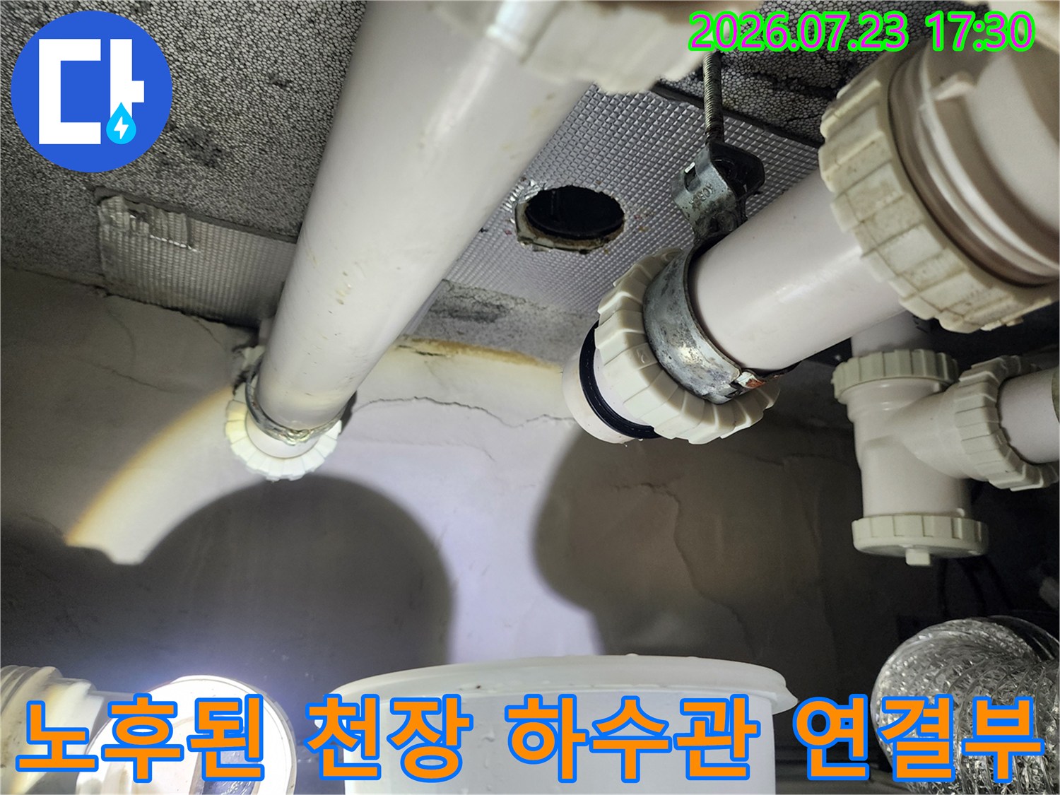 화장실 천장 속에 설치된 흰색 배수 파이프와 조임 부속-누수가 의심되는 지점의 근접 사진