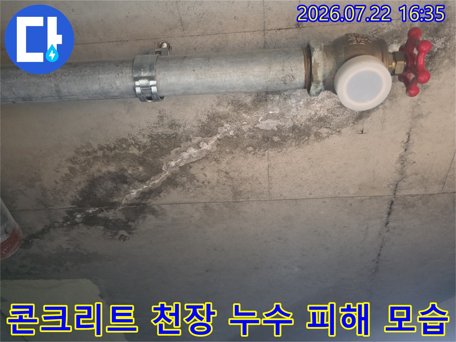 빨간색 밸브가 달린 배관 하단 콘크리트 면에 발생한 어두운 색의 누수 오염-사진