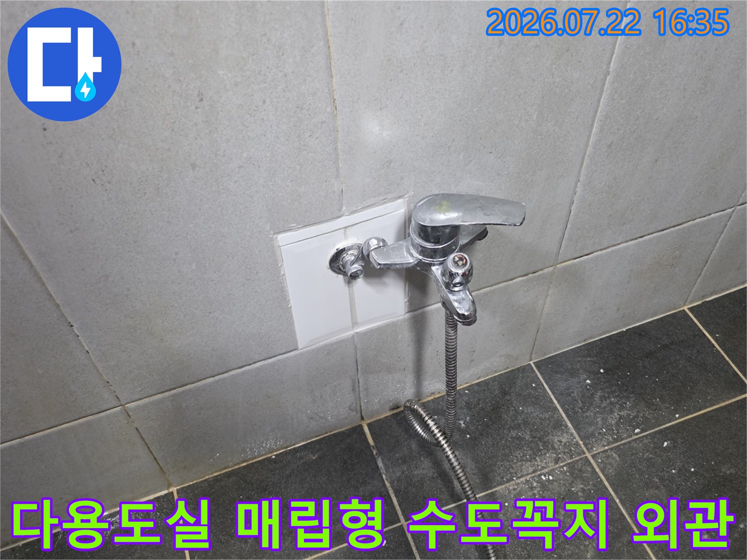 은색 수도C꼭지가 설치된 흰색 타일 벽면과 연결 호스-누수 탐지 부위