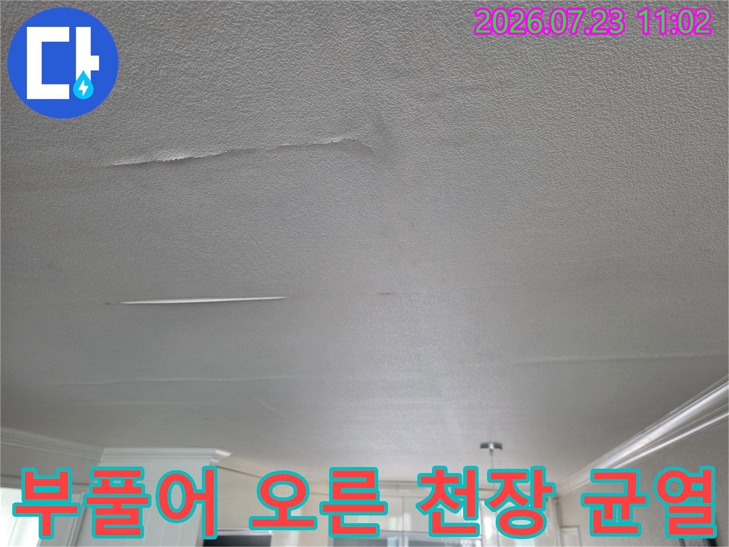 습기가 차올라 볼록하게 솟았다가 길게 갈라진 거실 천장의 마감재 모습