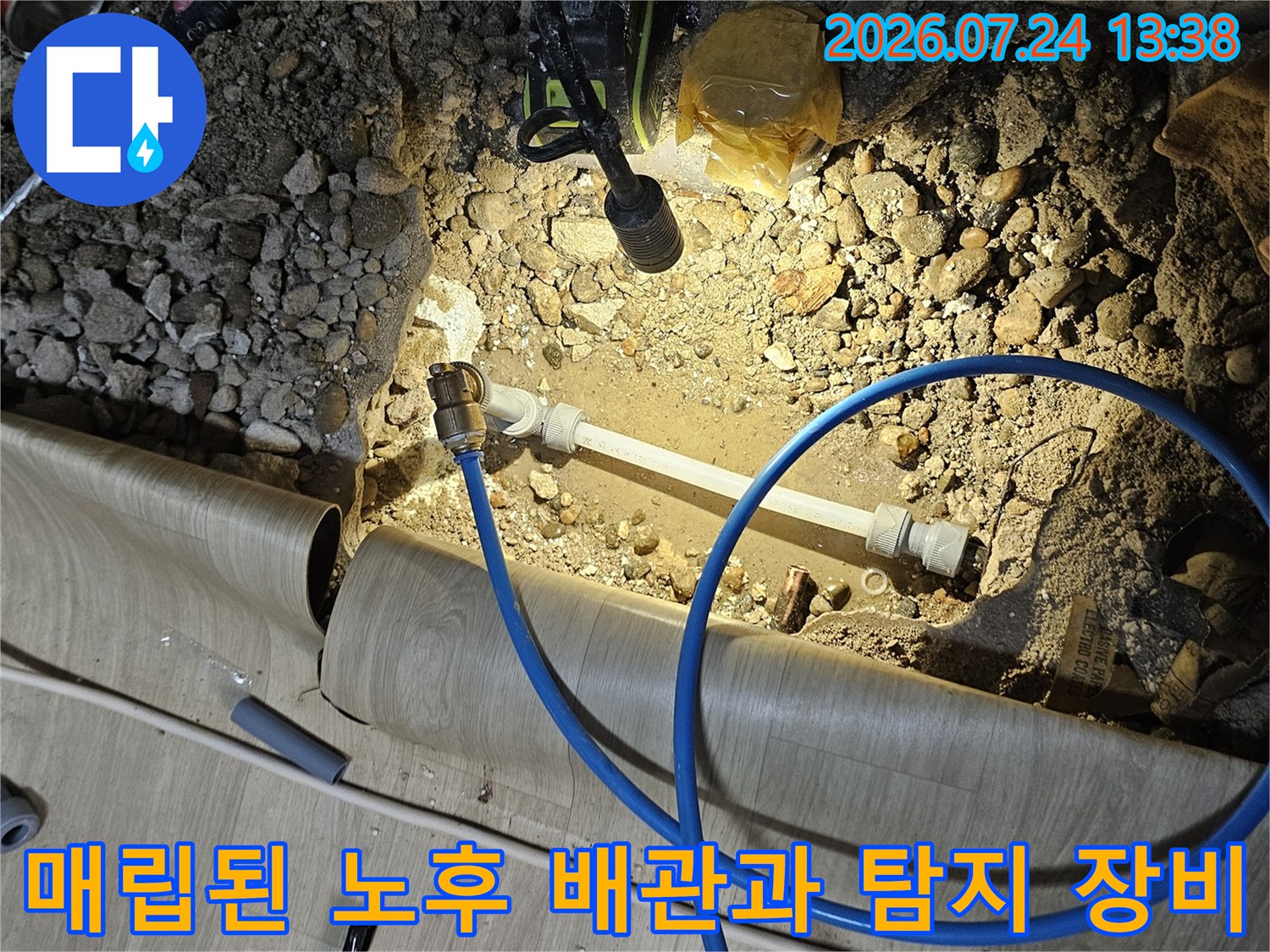굴착 부위 내부에 설치된 흰색 수도관과 연결된 파란색 측정용 호스-작업 사진