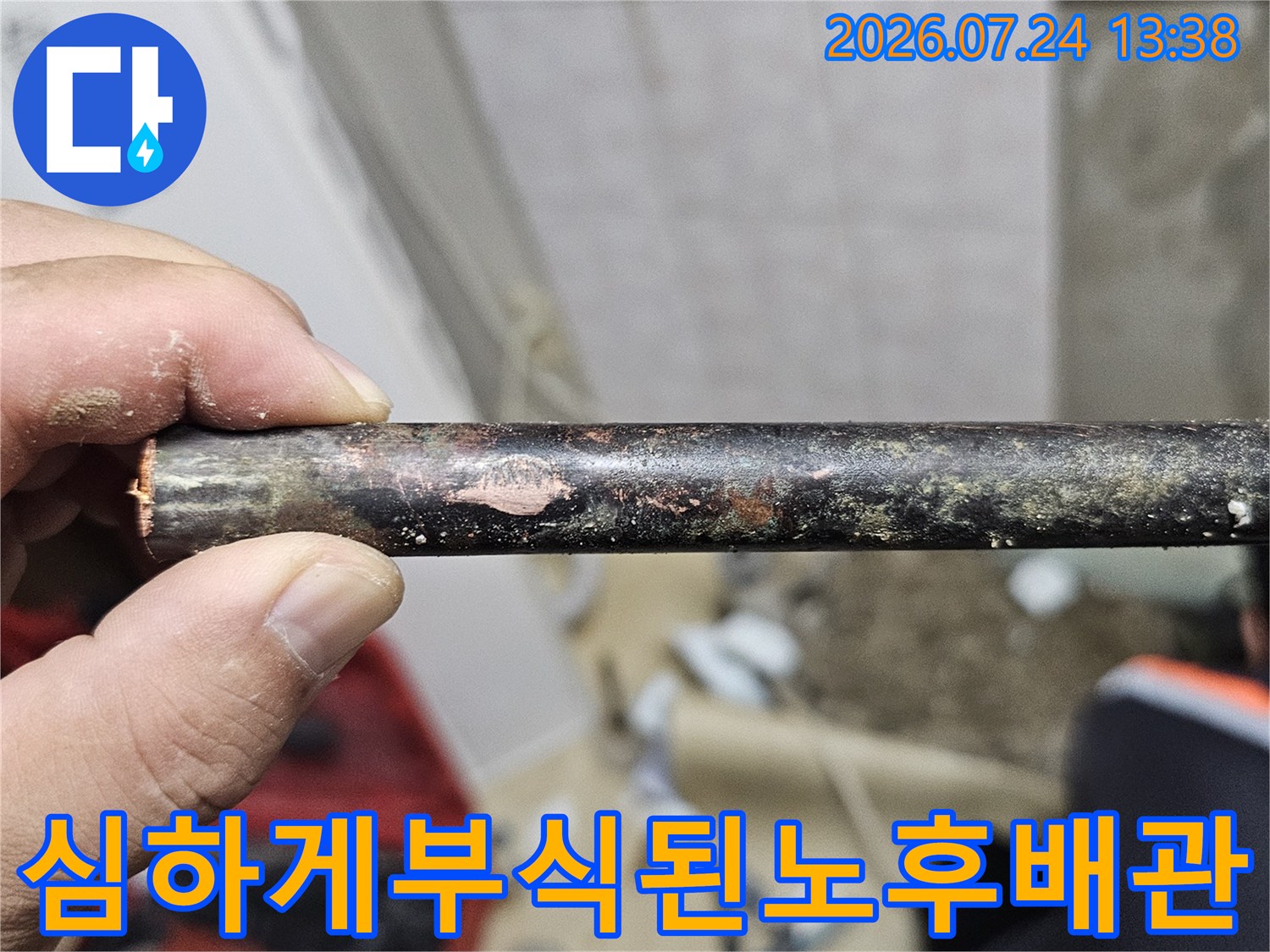 손으로 잡고 있는-표면이 검게 부식되고 손상된-금속제 노후 배관 사진