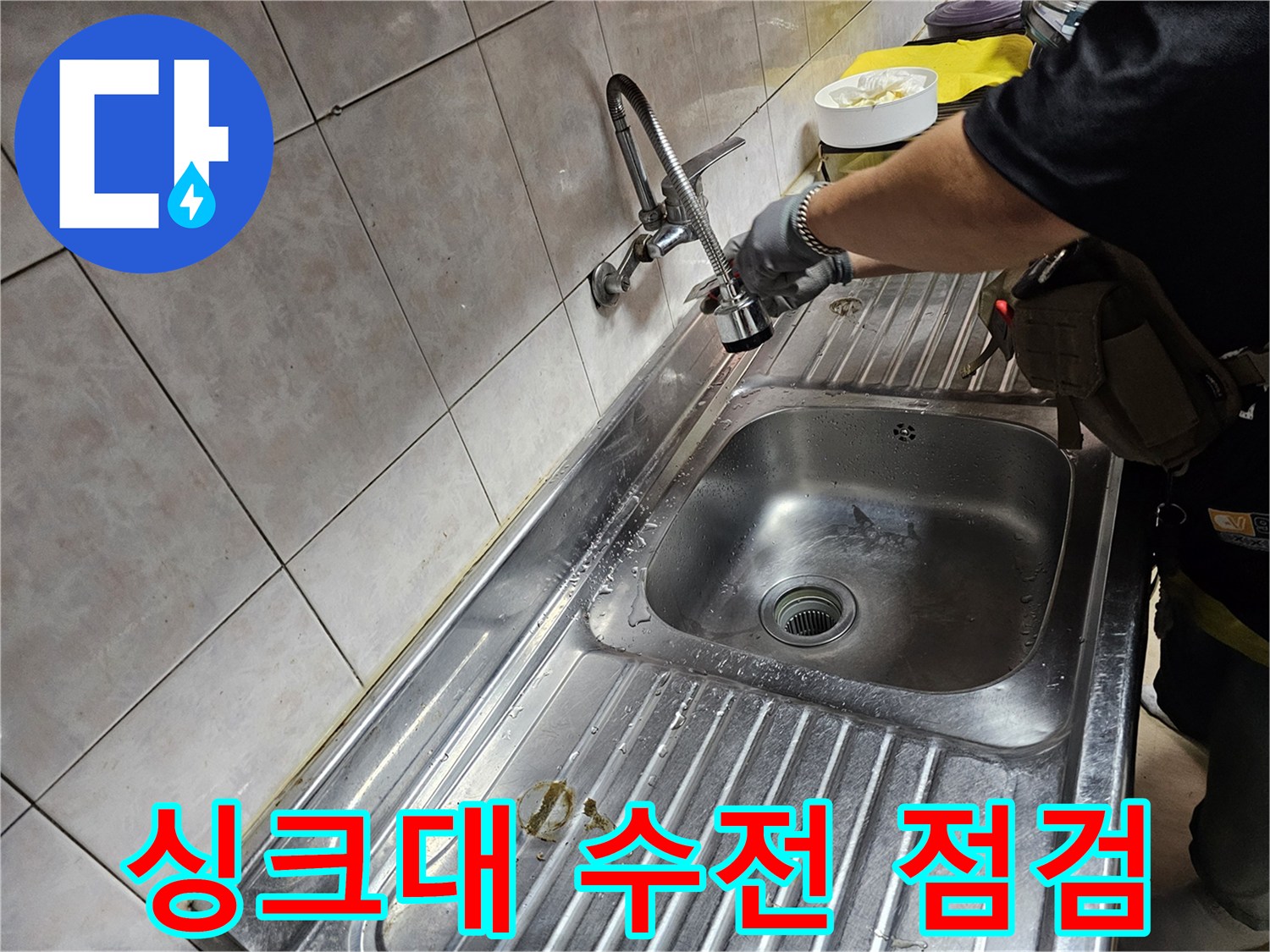 싱크대 배관 연결 부위의 누수 여부를 확인하는 작업자