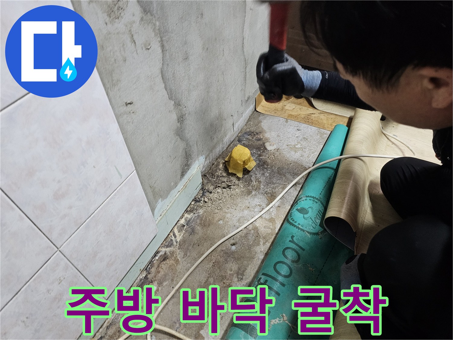싱크대 주변 바닥 타일을 제거하고 콘크리트 층을 드러내는 작업 현장입니다.