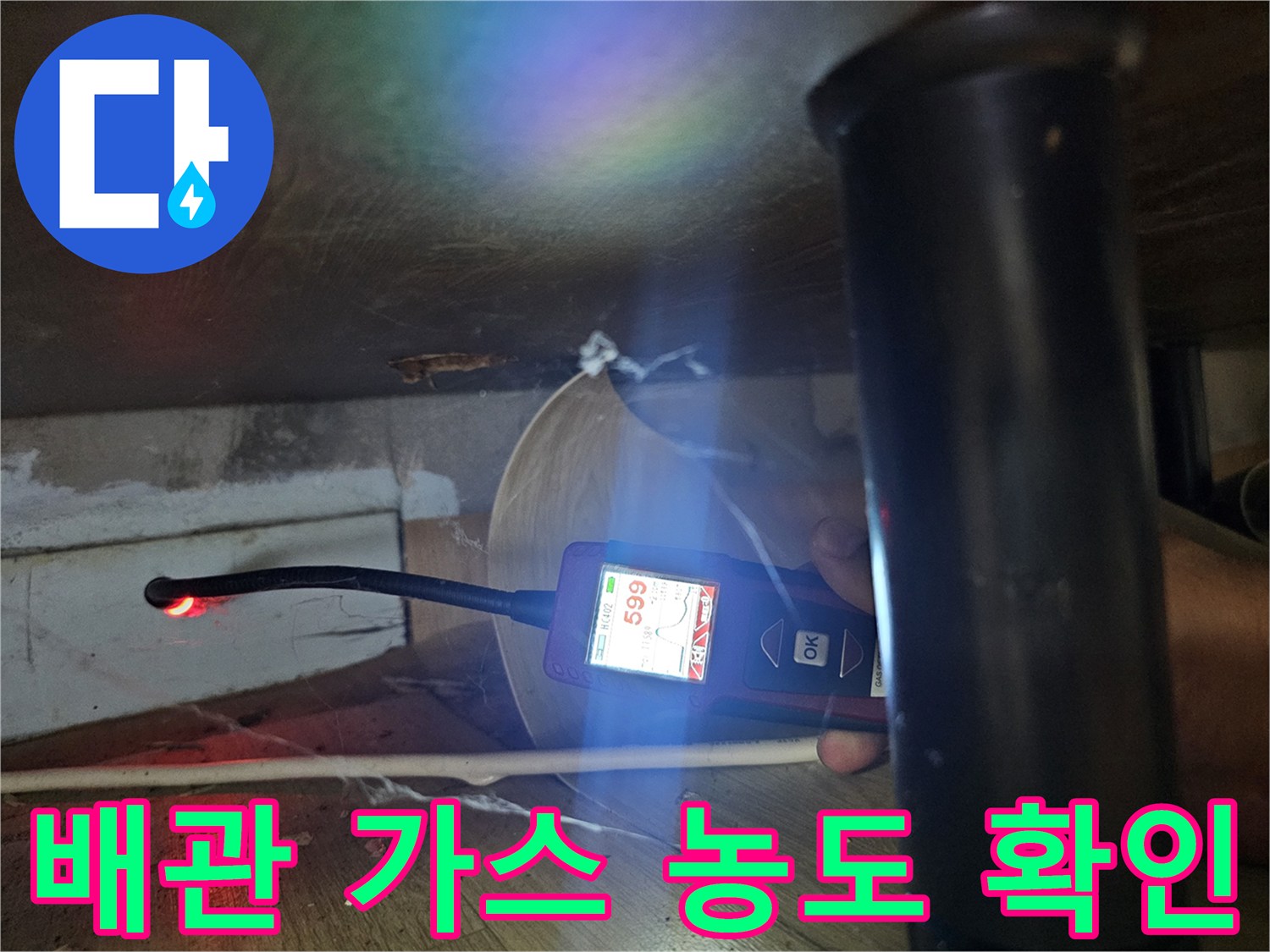 어두운 싱크대 밑 공간에서 가스 탐지기 센서로 수치를 체크하는 사진
