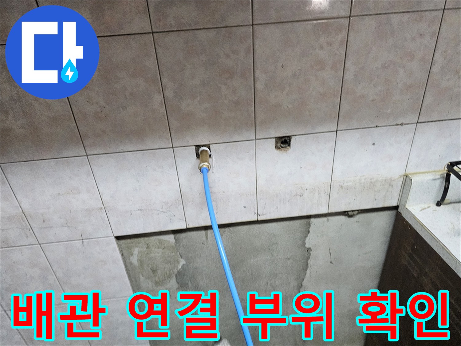 타일 벽면 틈새로 드러난 수도 배관과 점검 호스