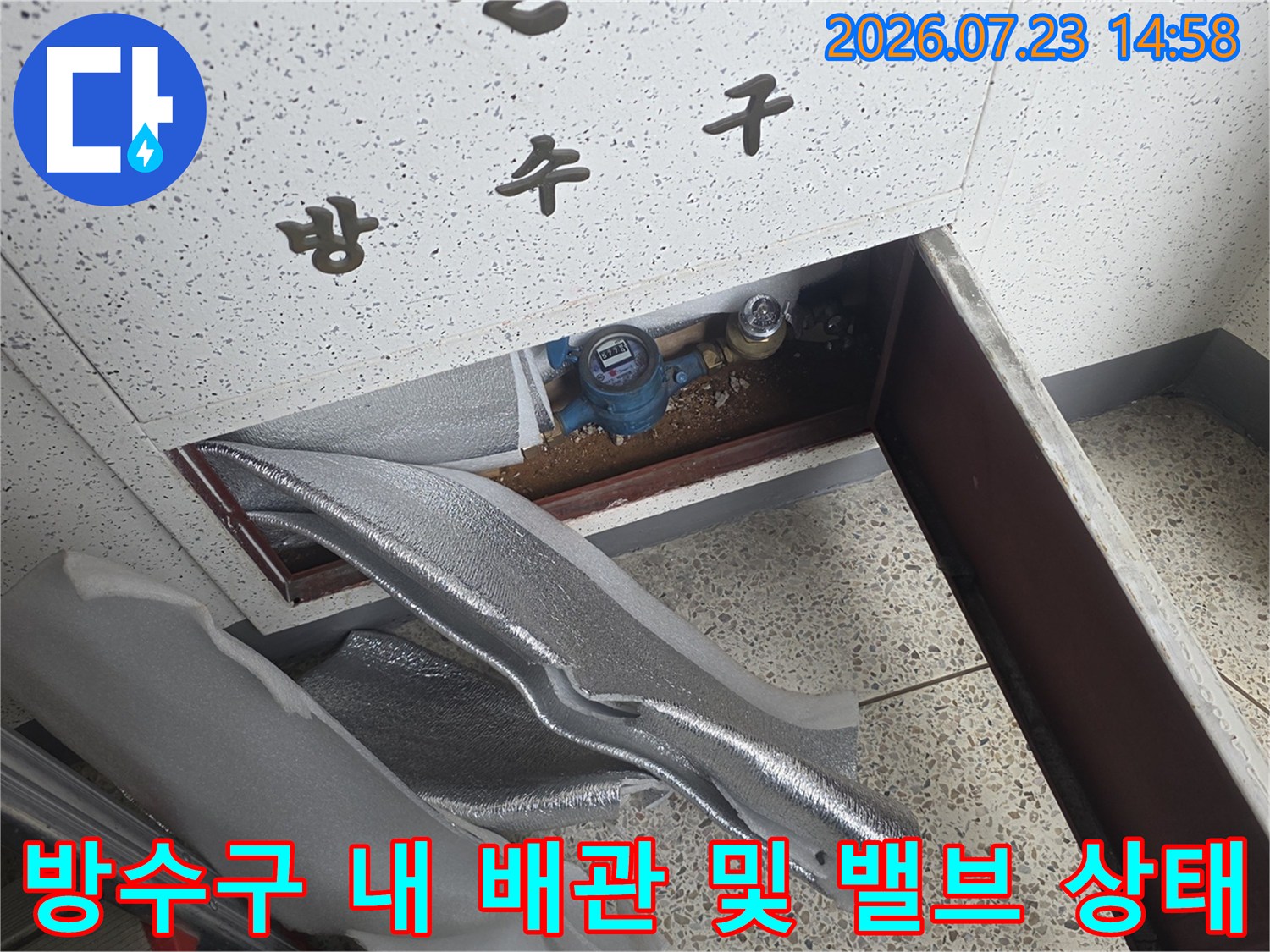 은색-보온재가-씌워진-배관과-파란색-조절-밸브가-들어있는-벽면-점검구-내부