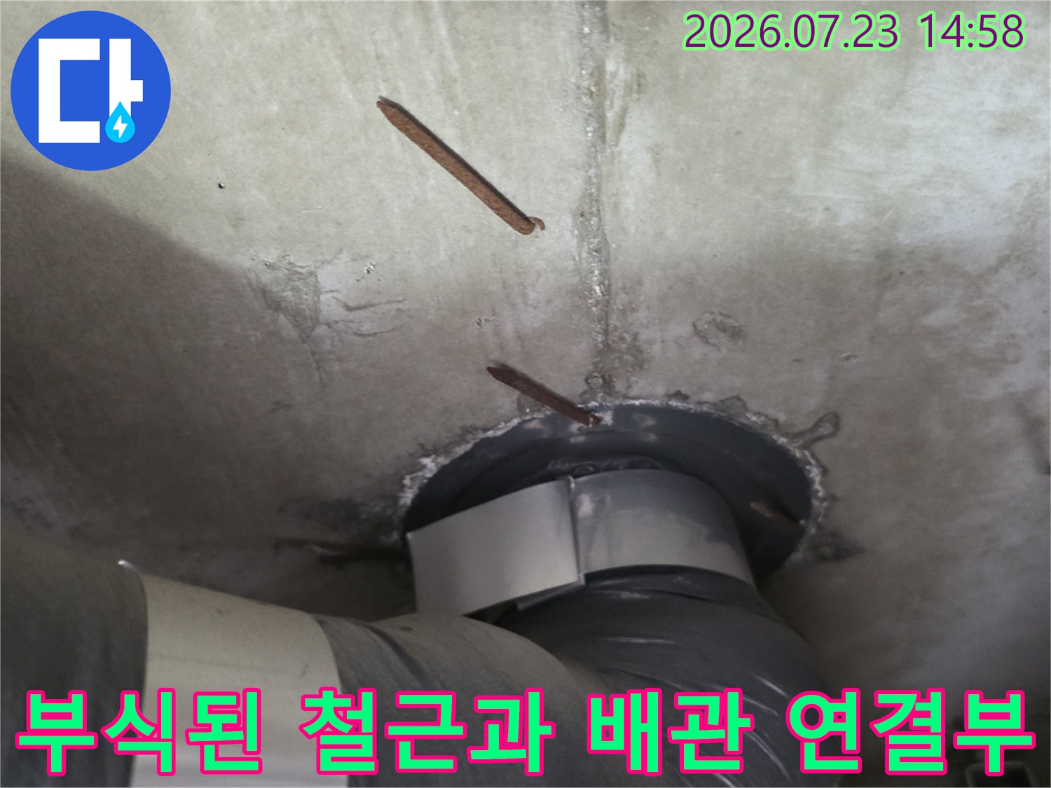 콘크리트 천장에서 노출된 부식된 철근-배관 연결 부위 사진