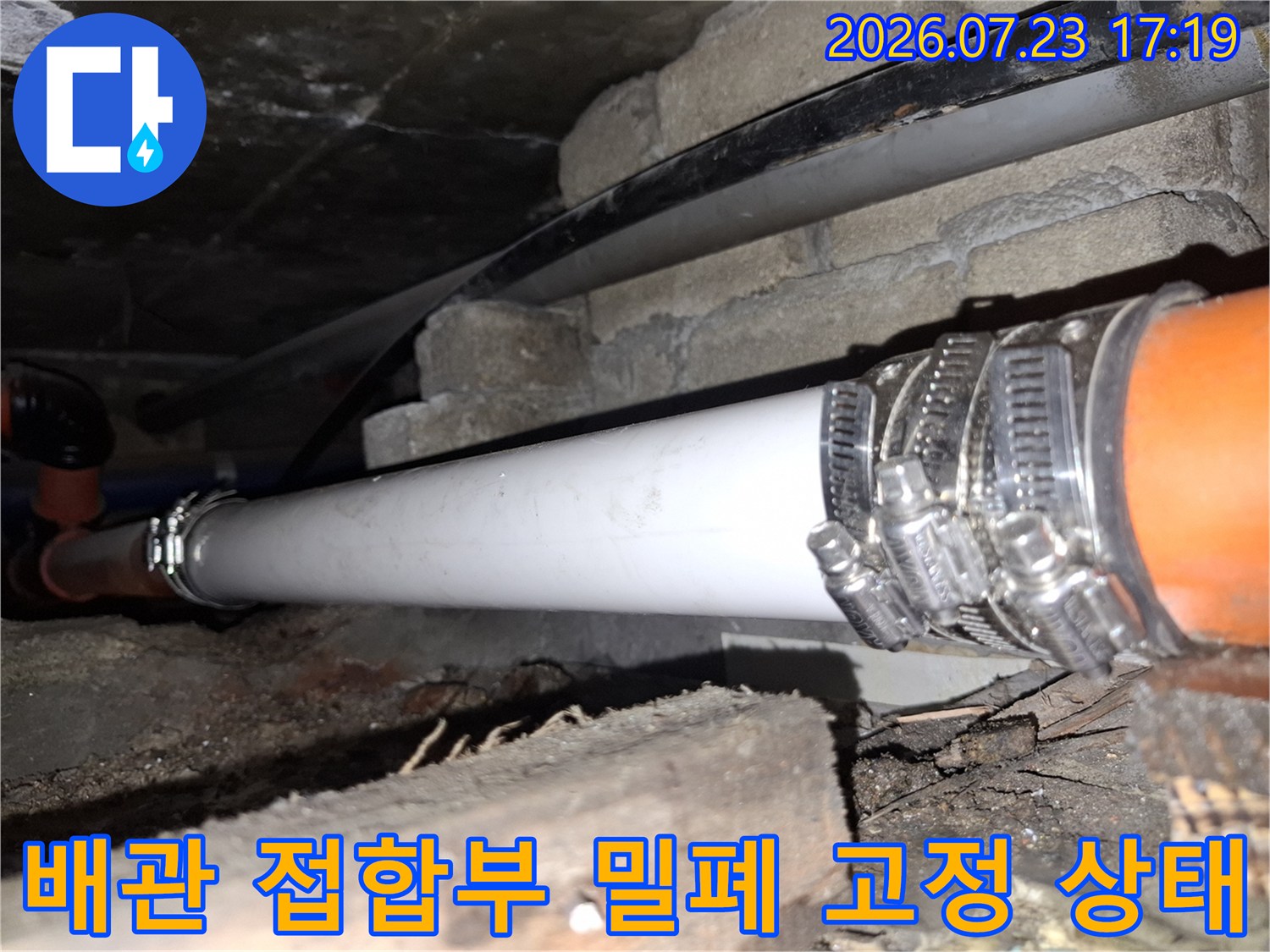 흰색 배관과 오렌지색 배관의 연결 부위를 금속 밴드로 촘촘하게 조여놓은 모습