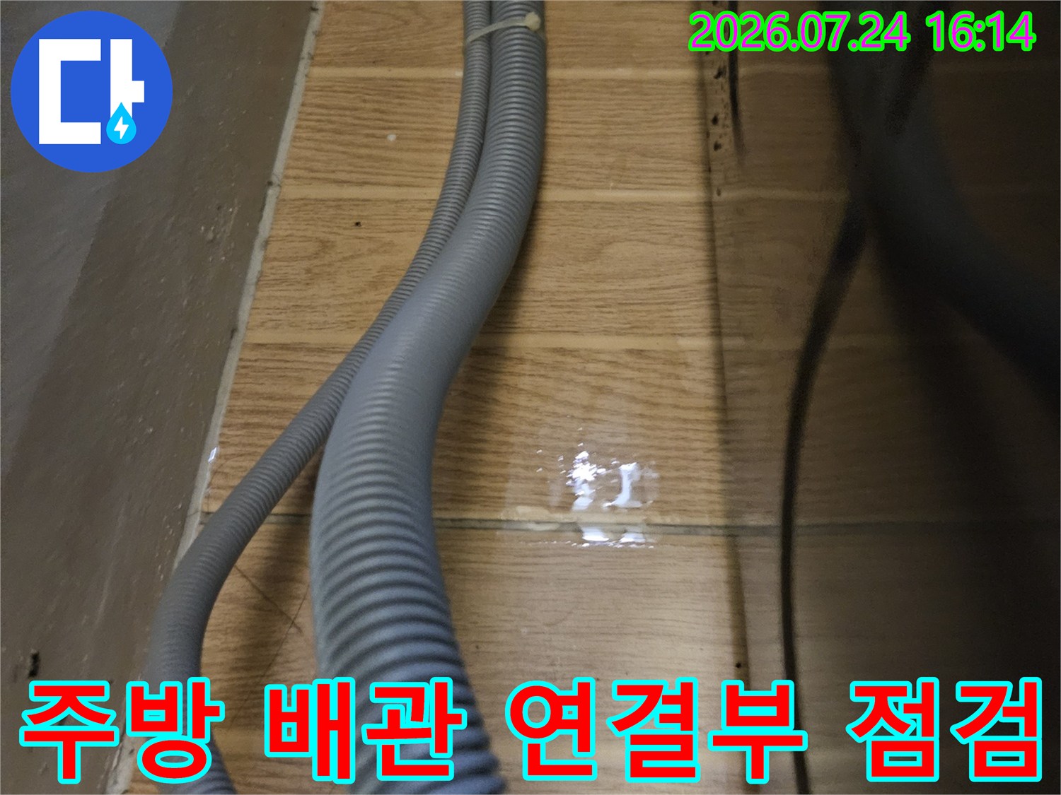 벽면으로 이어지는 주방용 회색 배수 호스의 굴곡진 구간과 결합 부위 상세 촬영