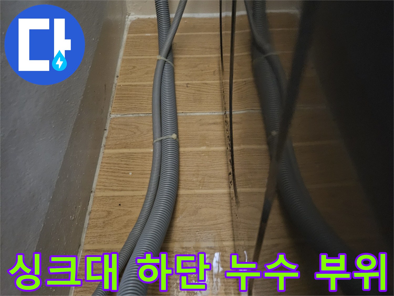 싱크대 아래쪽 젖은 타일과 연결된 배수관 사진