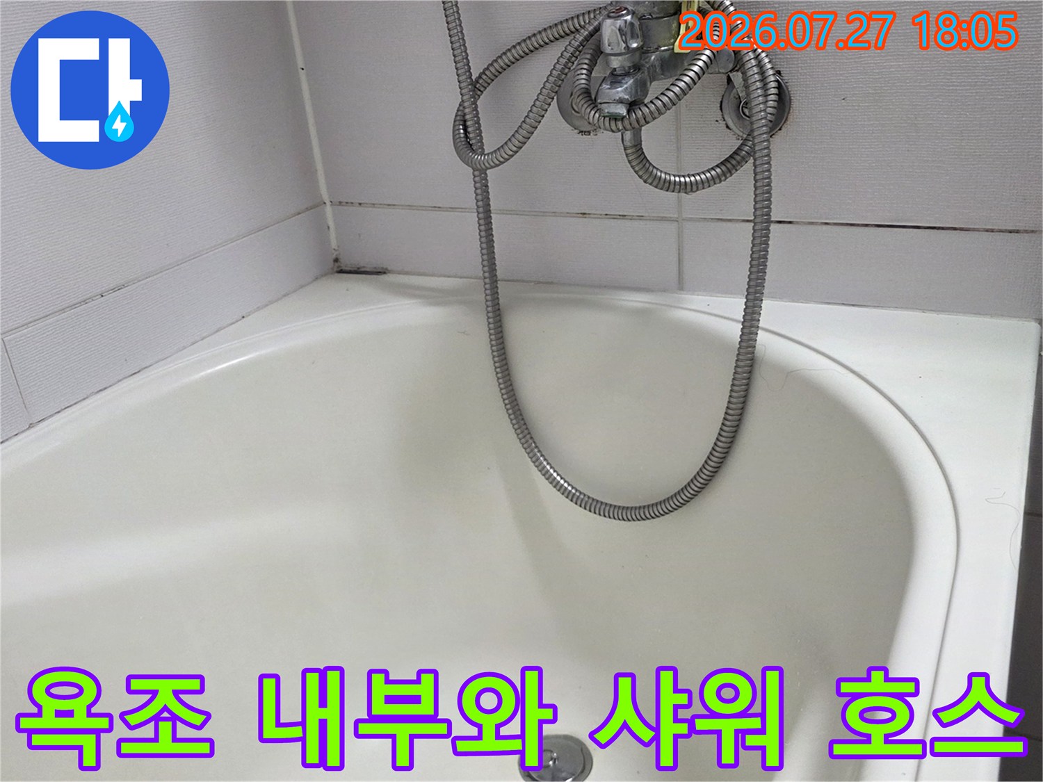 흰색 욕조 본체와 벽면에 고정된 은색 샤워기 수전-호스 모습