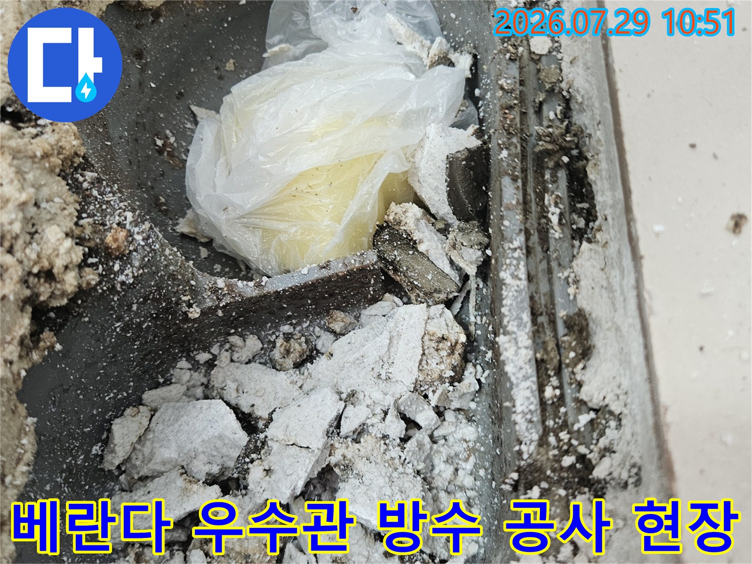 손상된 베란다 우수관 주변의 파손된 방수층과 노출된 배관 부위