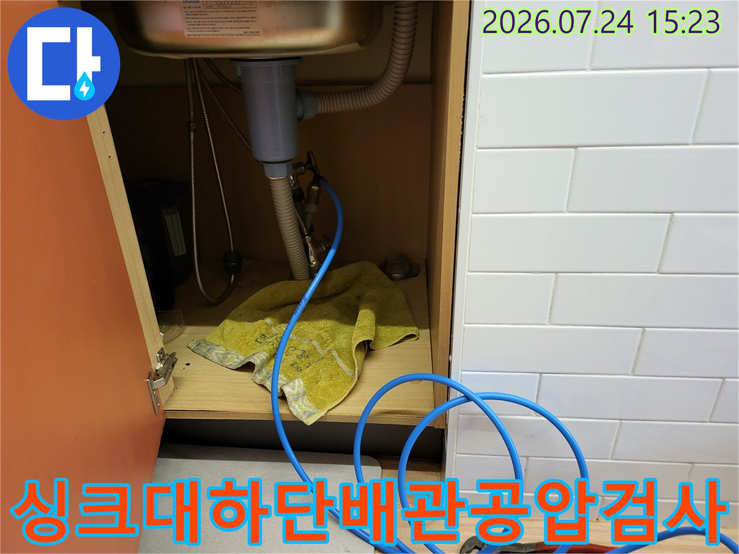싱크대-하부장-내부에-파란색-공압-테스트-호스를-연결하여-누수-점검을-진행하는-모습