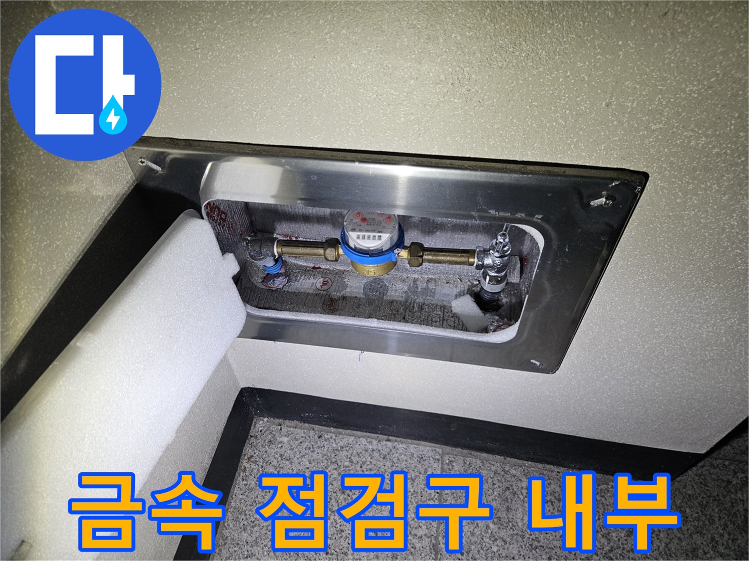 벽면 스테인리스 커버 안쪽에 보이는 수도 계량기와 배관 부속