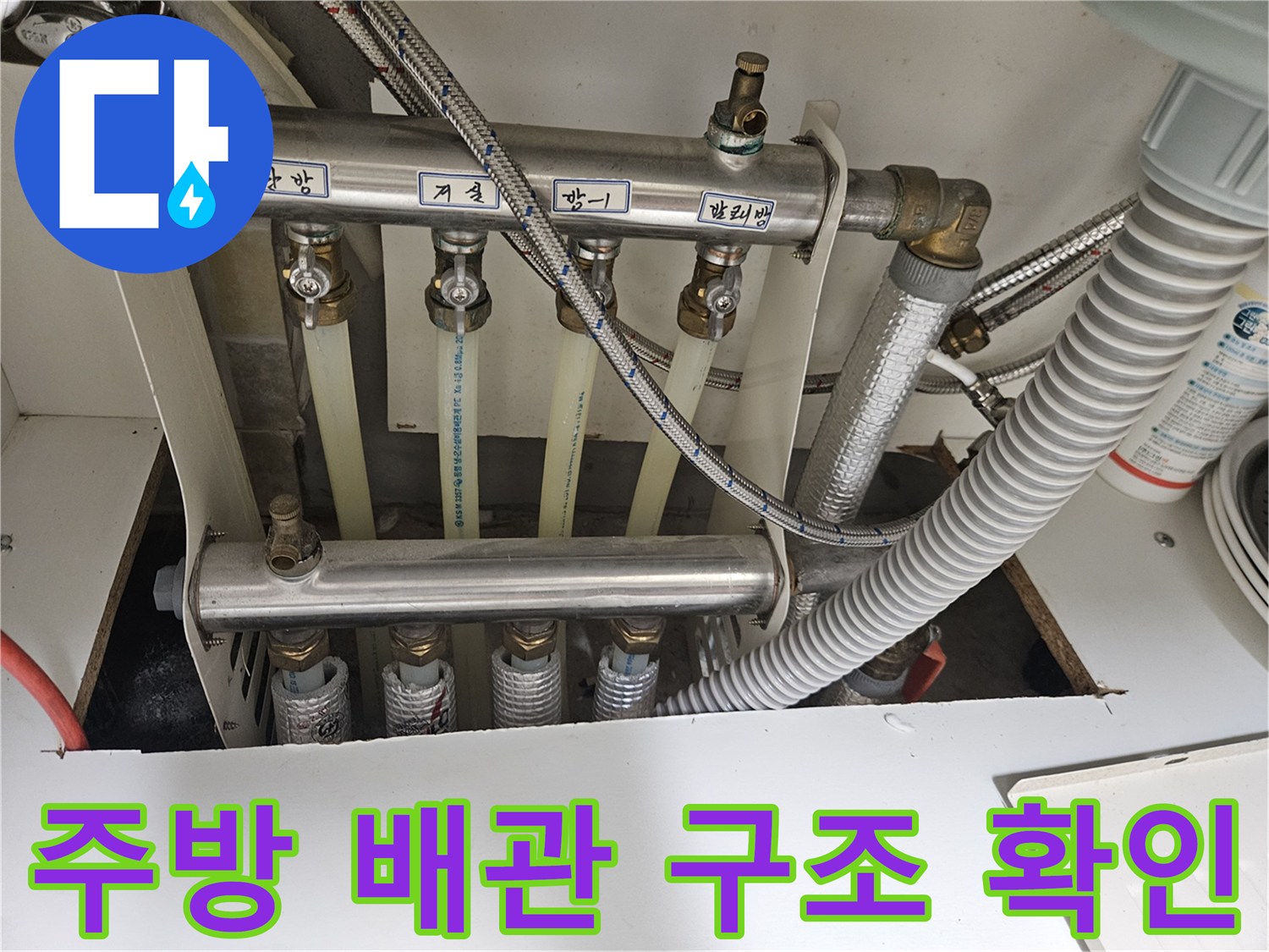 싱크대 하부의 금속 지지대와 연결된 다양한 배관들