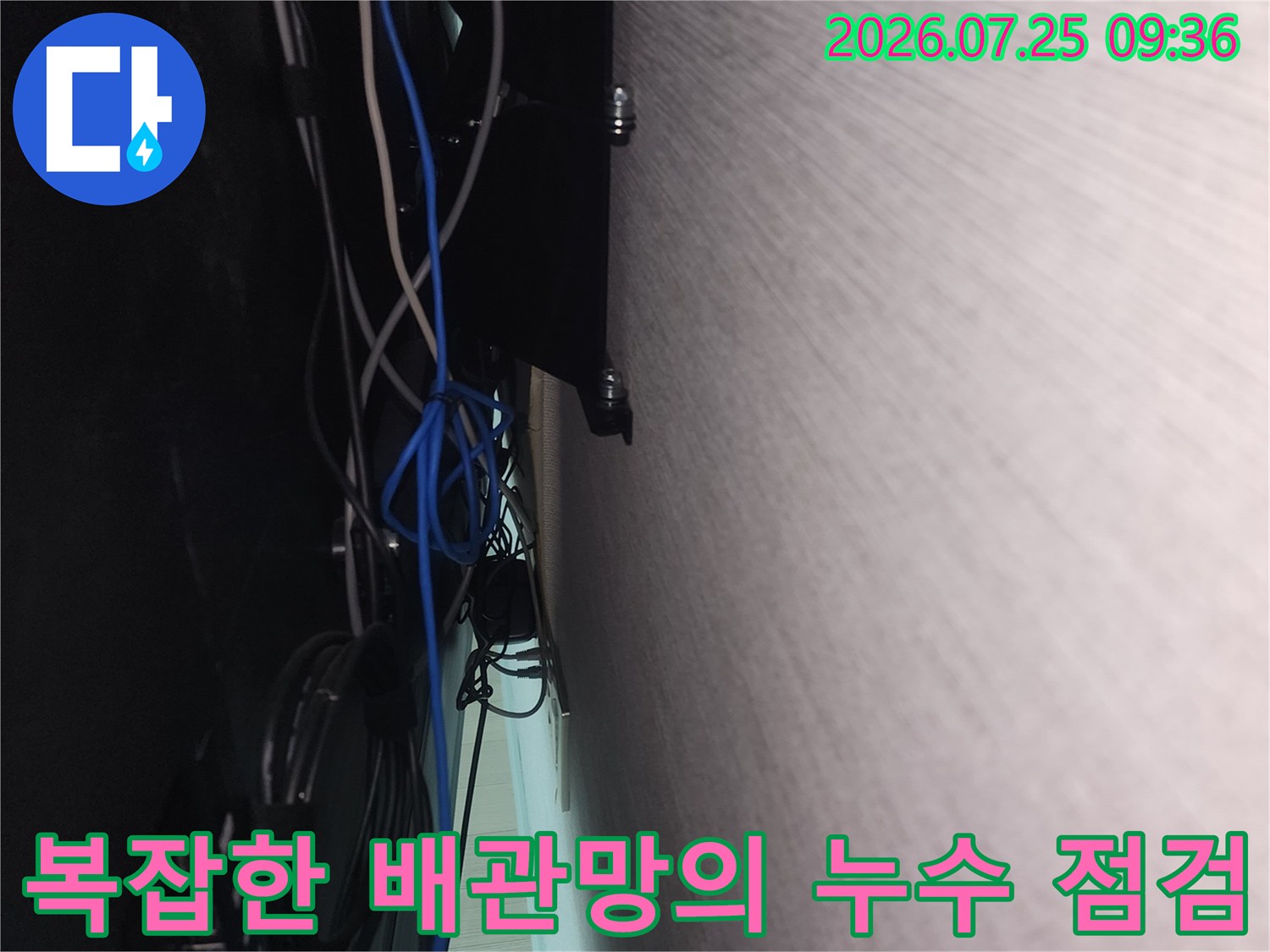 벽 하부 공간에 설치된 여러 가닥의 파란색 배관 연결 상태