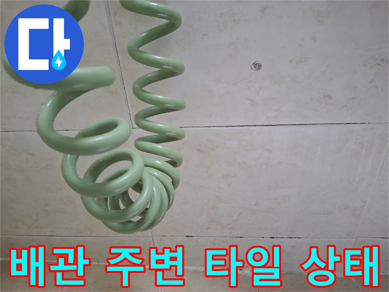타일 벽면과 초록색 배관의 접합 부위 상세 사진