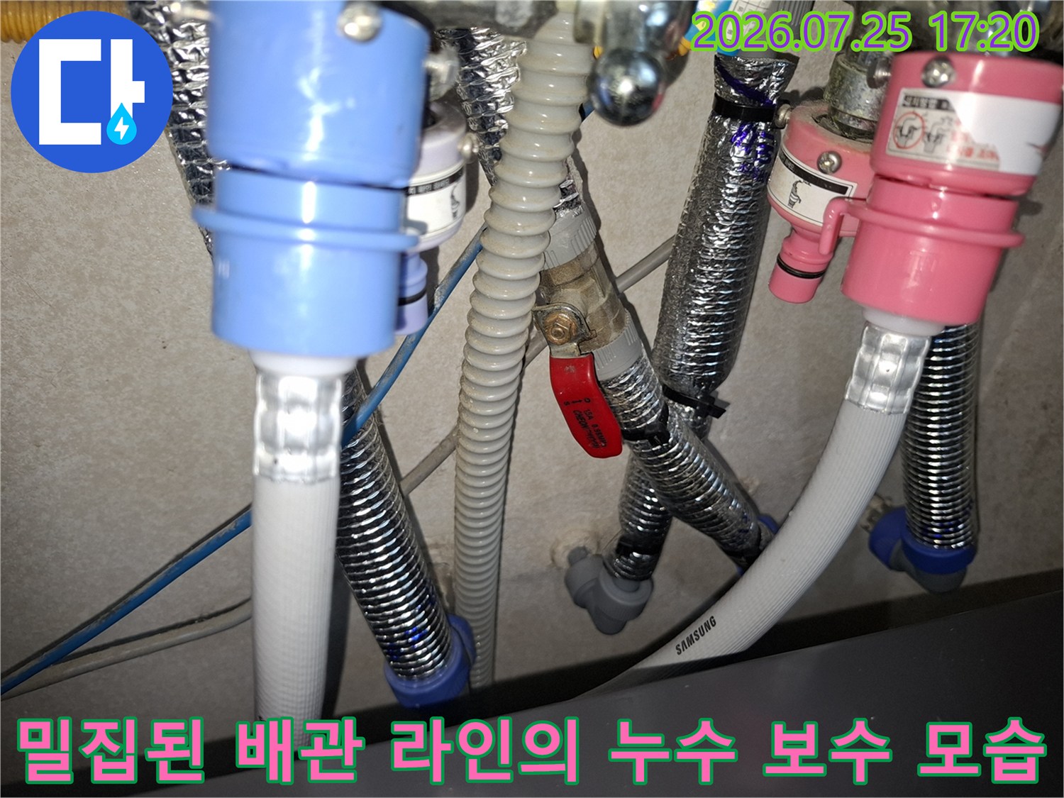 삼성 표기가 된 흰색 배관과 여러 색상의 연결 부품들이 얽혀 있는-누수 수선 현장