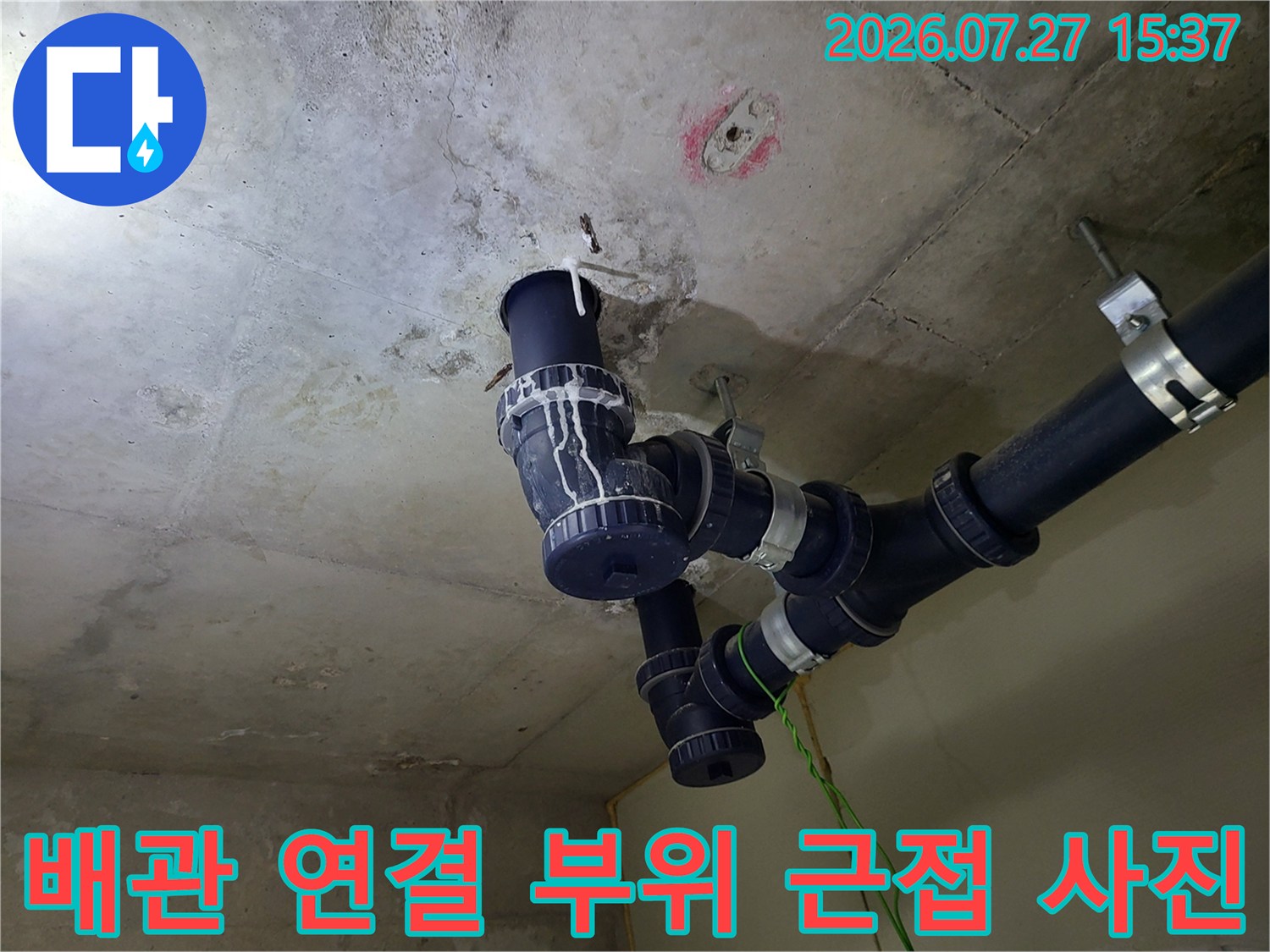 천장에 고정된 검정색 하수 배관의 엘보 및 소켓 연결 부분